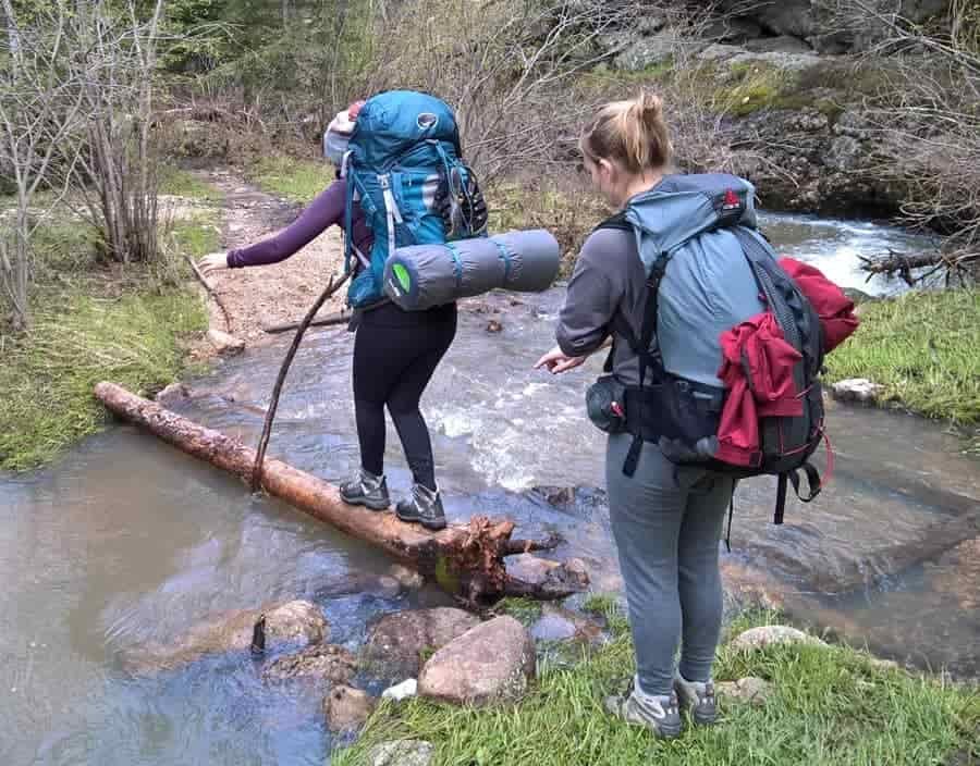 long distance walkers crossing river in hiking boots