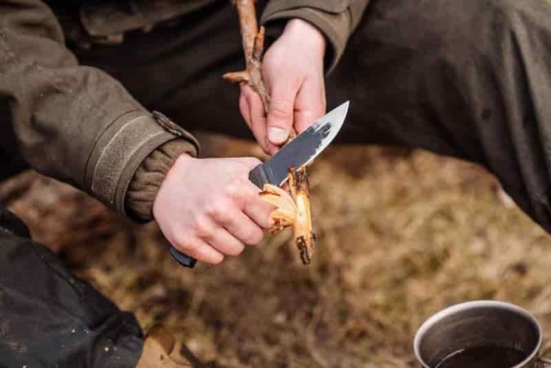 Bushcraft skills sharpening stick near pant legs